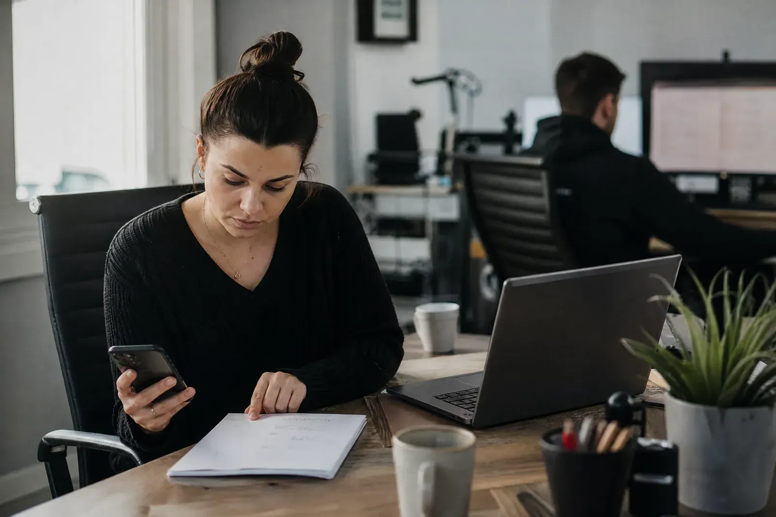 The owner of a small service business compares four different lead counts for the same month, written on a notepad next to an open laptop and a phone.