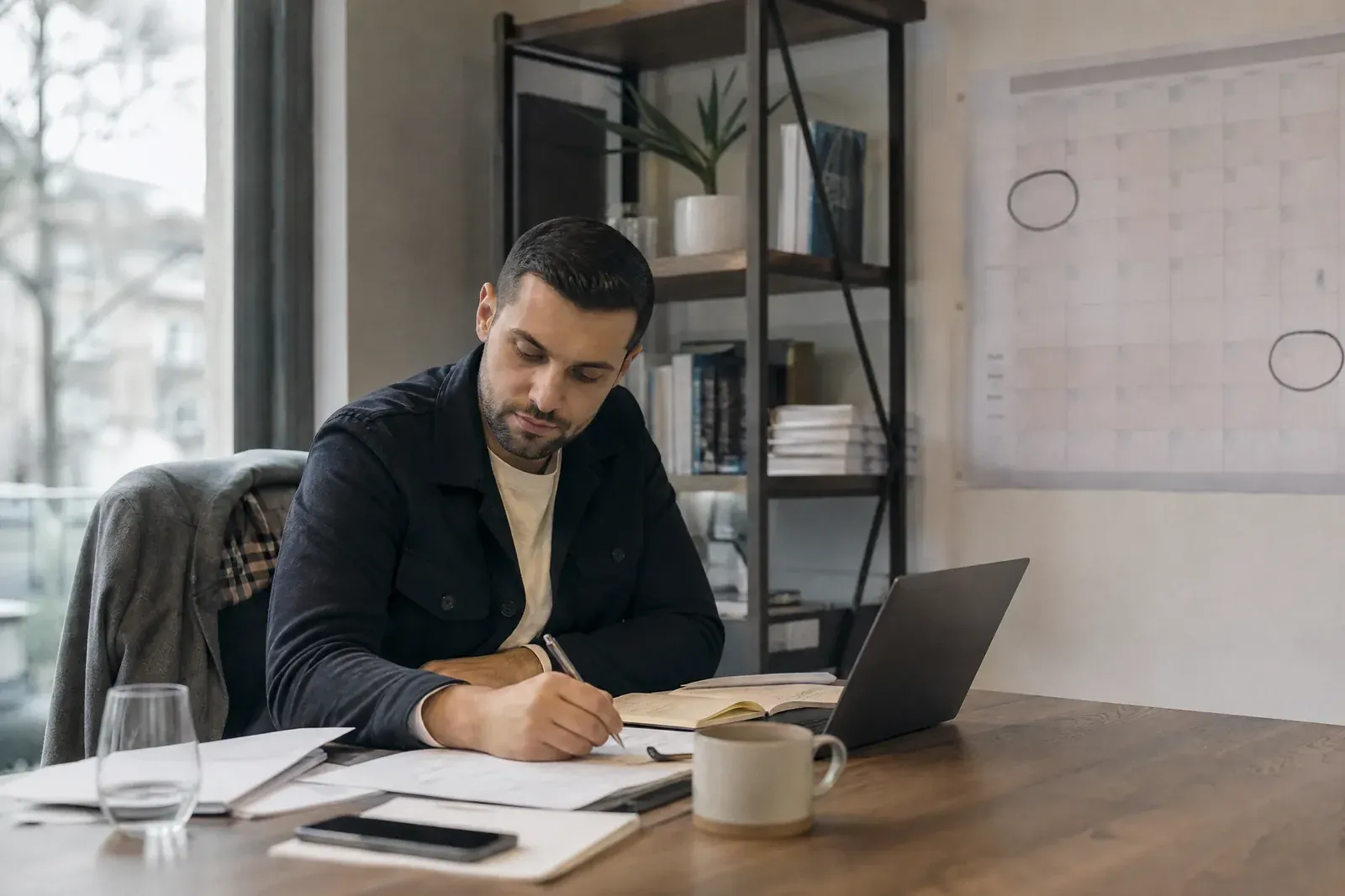 A small business owner at a desk plans the next busy season, with a wall planner showing late November and next spring circled.
